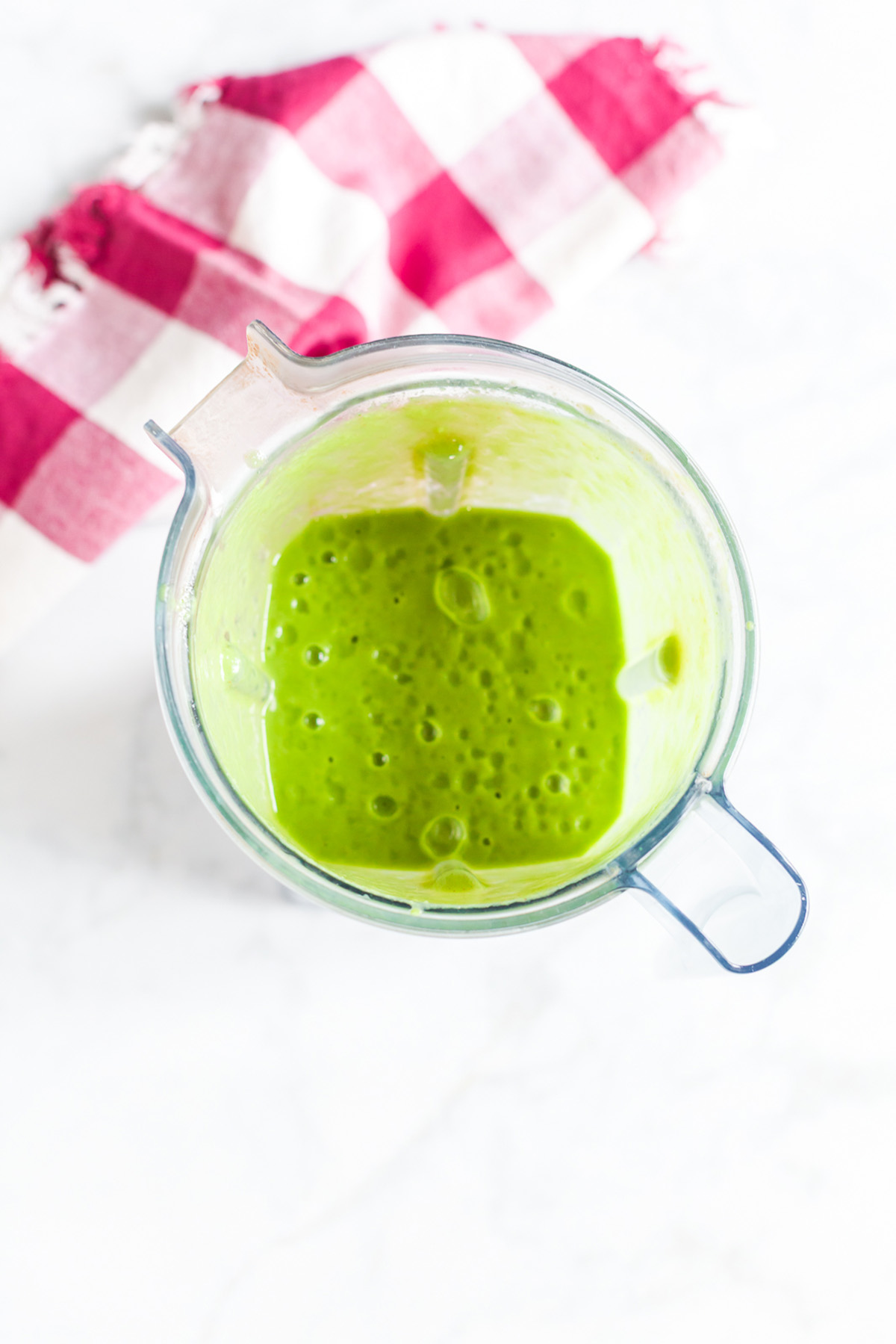 Smooth and creamy spinach apple smoothie blended in a blender jar, bright green in color.