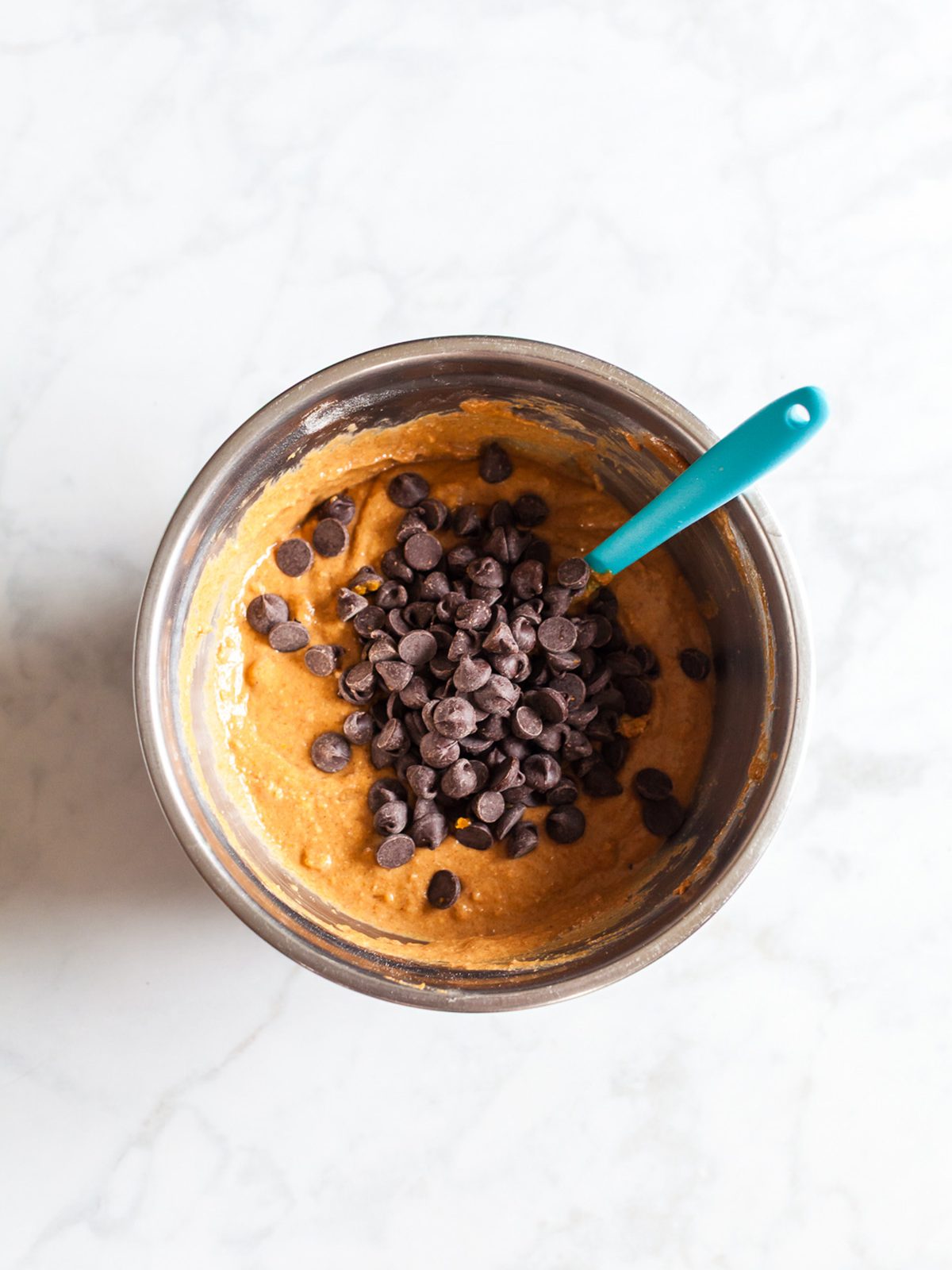 Folding chocolate chips into pumpkin oat cookie batter for soft and chewy pumpkin breakfast cookies.