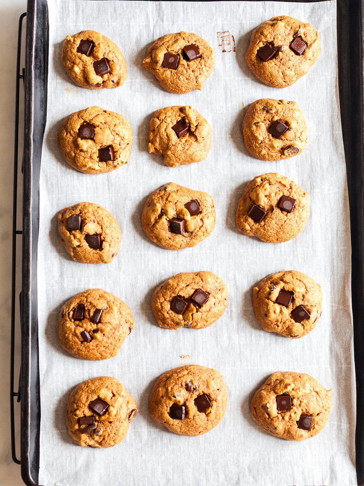 Freshly baked pumpkin breakfast cookies with chocolate chunks cooling on a parchment-lined baking sheet, soft, chewy, and full of pumpkin spice flavor.