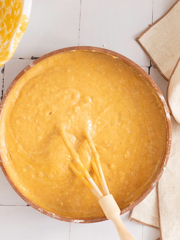 Pumpkin bread batter mixed until smooth and creamy in a large wooden bowl, ready to pour into a loaf pan.