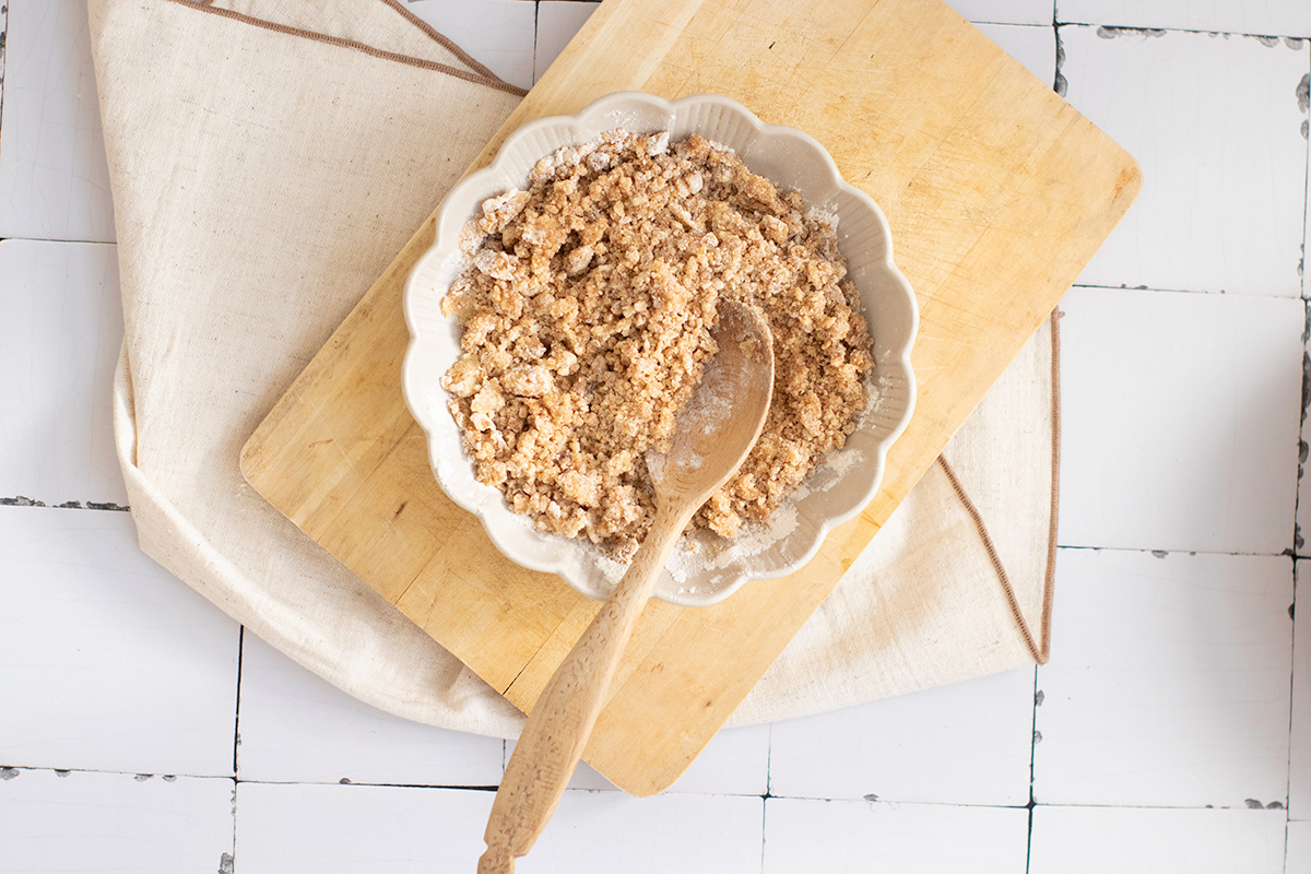 Making the streusel topping for pumpkin bread, brown sugar, flour, and butter combined in a small bowl with a wooden spoon.