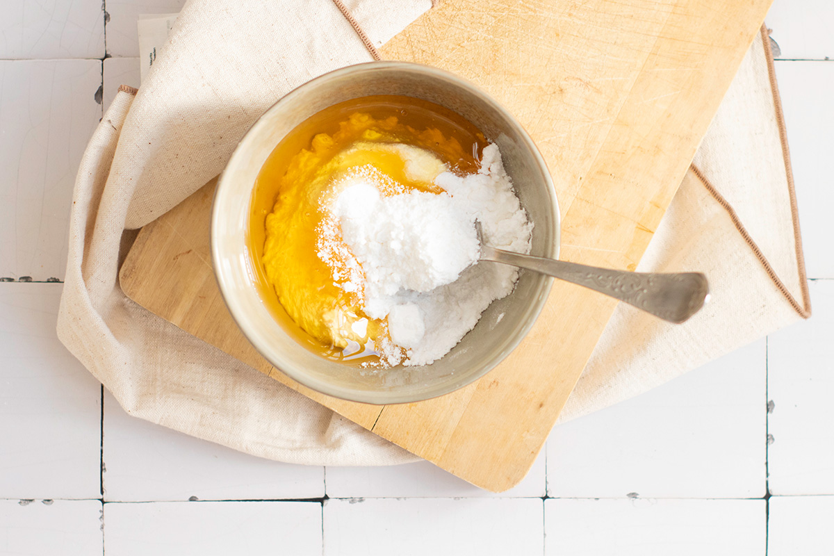 Honey glaze being prepared with powdered sugar and honey in a small bowl to drizzle over baked pumpkin streusel bread.