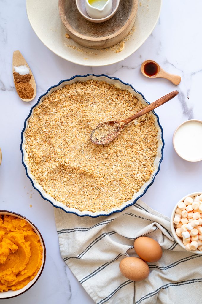 Graham cracker crumbs mixed with melted butter and sugar in a pie dish to form the crust for sweet potato s’mores pie.