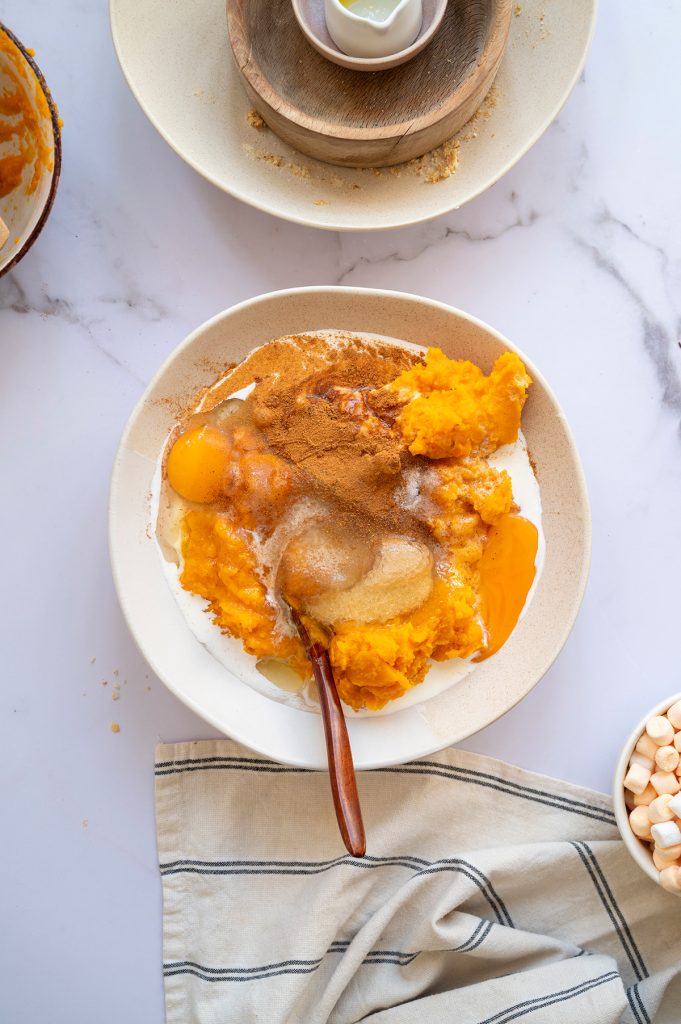 Sweet potato and pumpkin filling mixture in a bowl with eggs, cream, brown sugar, and spices ready to be blended together.