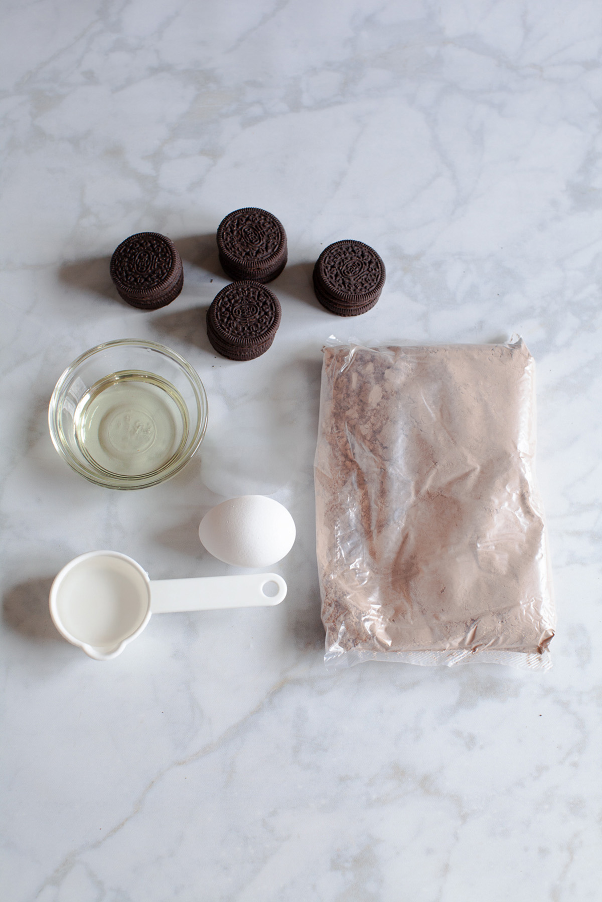 Baking ingredients for Oreo-stuffed brownie cups including cookies, brownie mix, egg, oil, and water.