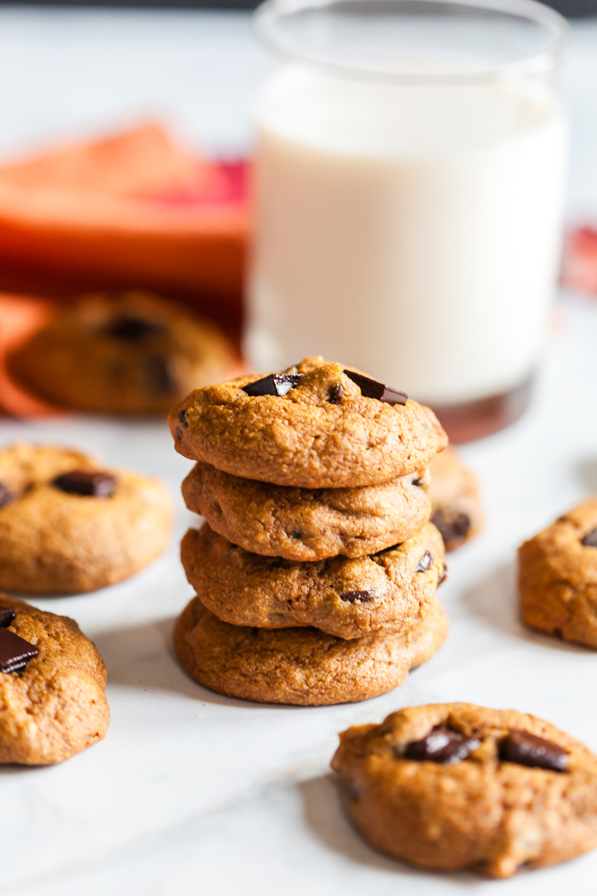 Stacked healthy pumpkin breakfast cookies with melty chocolate pieces and a glass of milk in the background, perfect for an easy fall morning snack.
