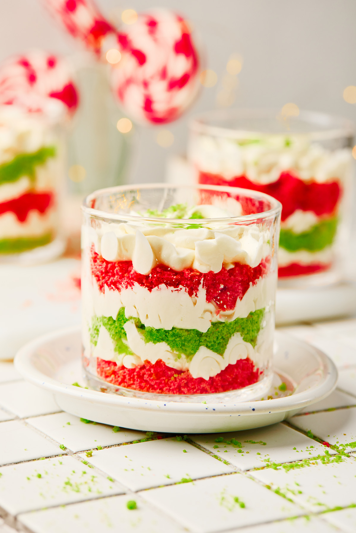 A fun and festive Christmas trifle dessert made with crumbled red and green cakes and an easy, fluffy cream cheese filling that tastes like the holidays in every bite. Easy Christmas trifle dessert served in a glass with red and green cake crumbs and creamy filling.