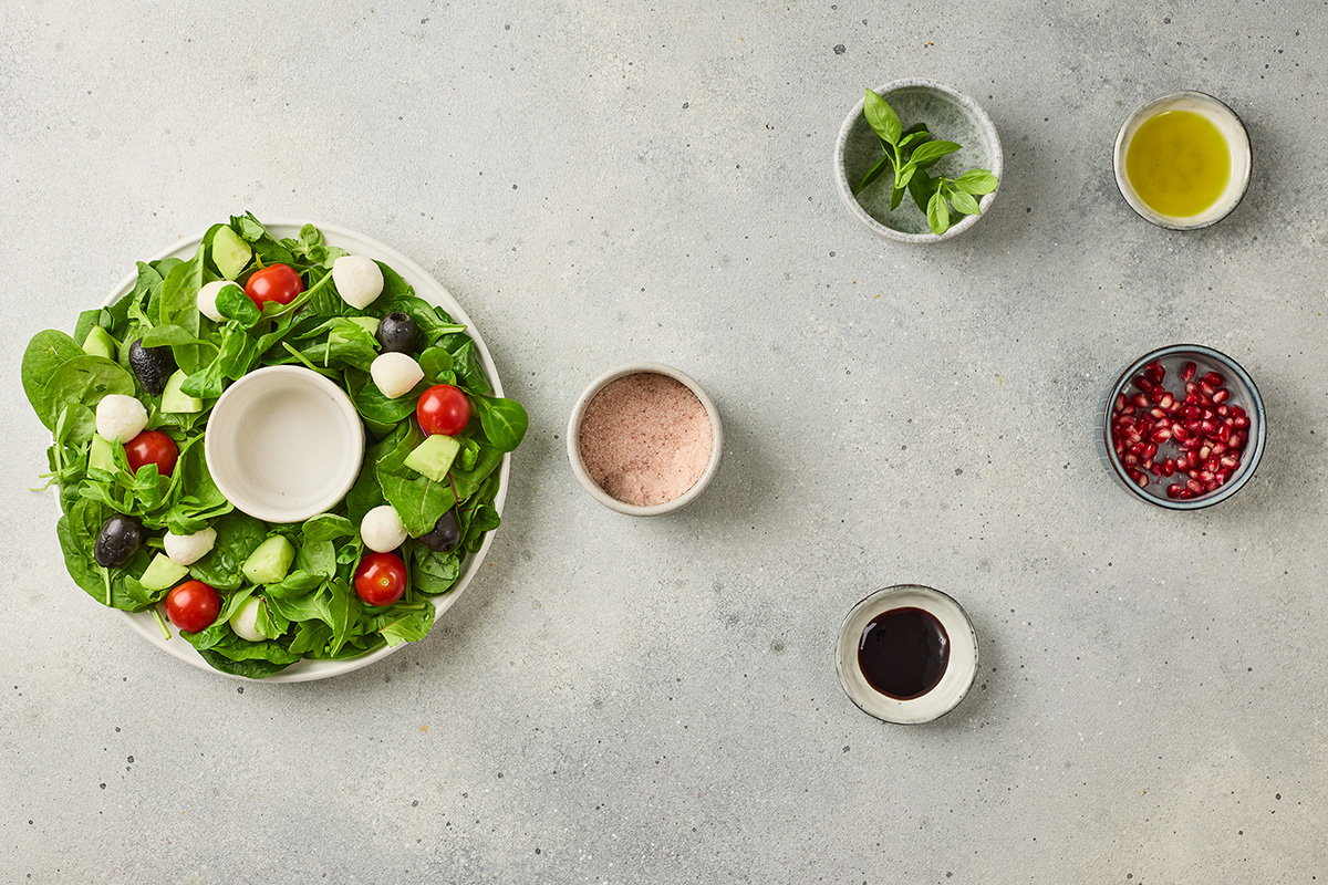Plate arranged with mixed greens in a circular wreath shape as the base of a Christmas salad.