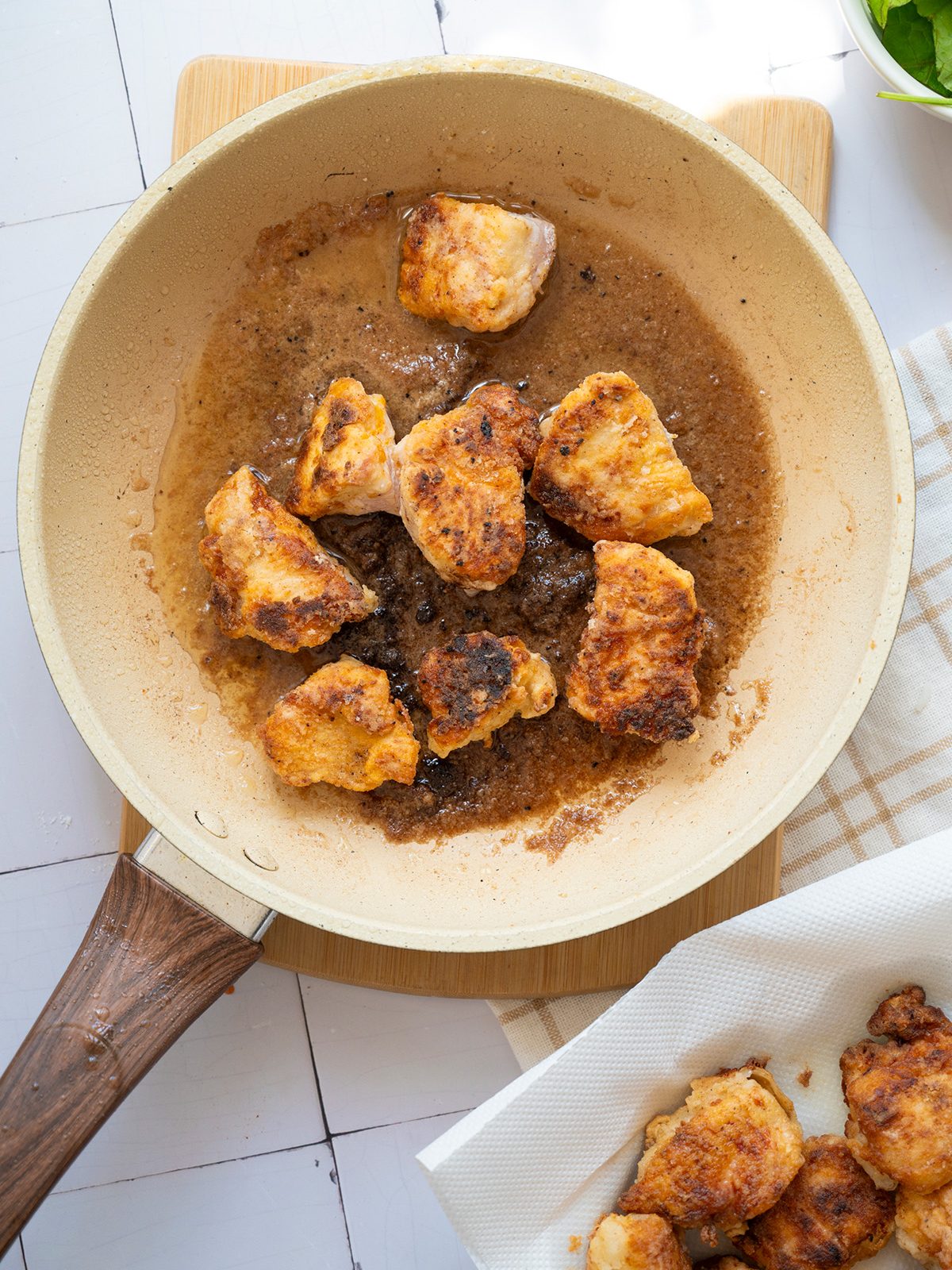 Crispy coated chicken frying in a skillet, showing golden edges and bubbling oil as the pieces cook through.
