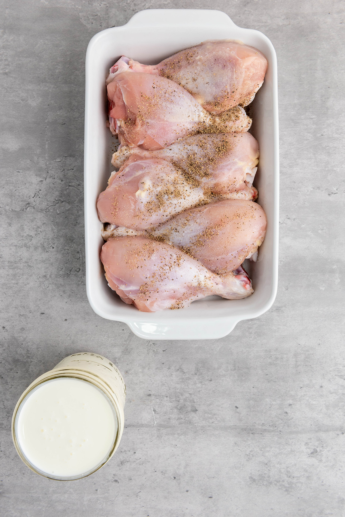 Raw drumsticks seasoned with salt and pepper, ready for the buttermilk marinade.