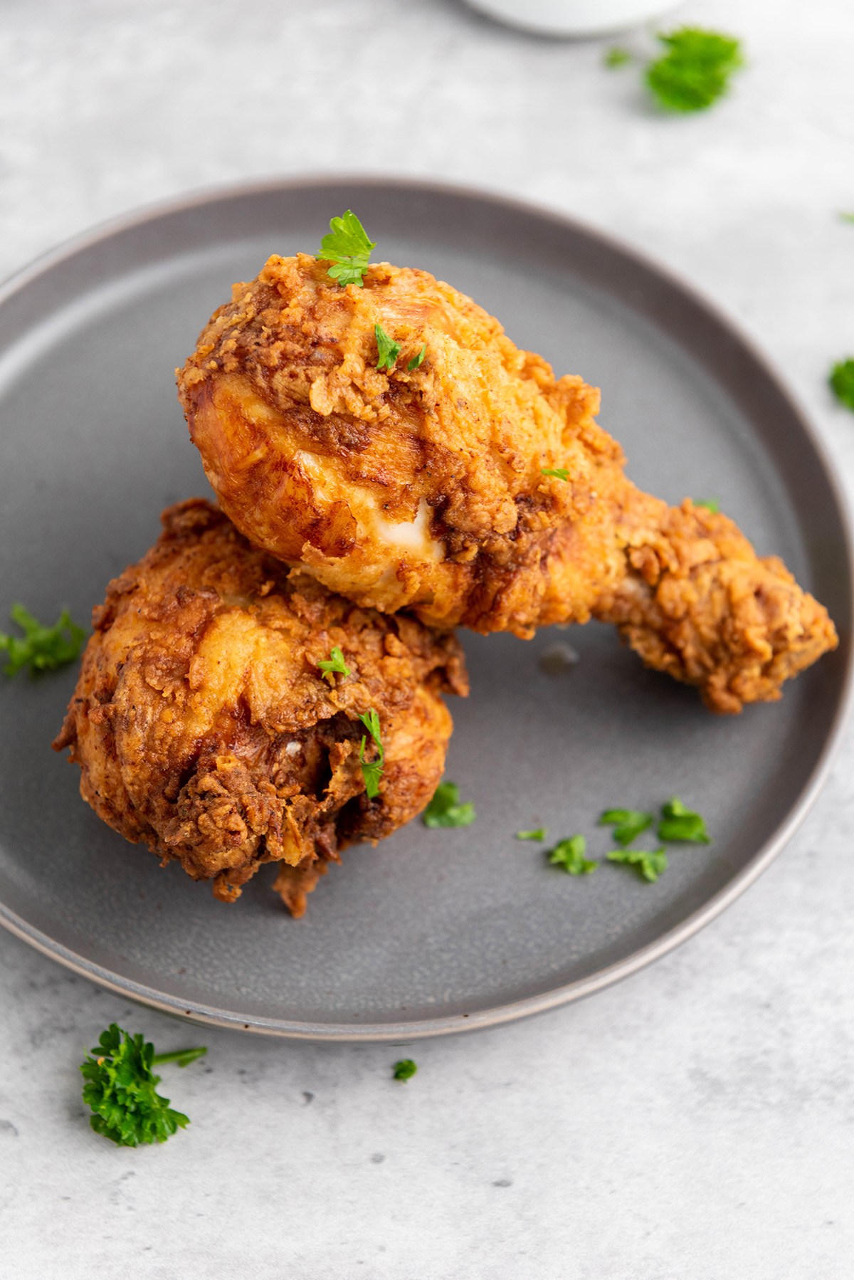 Chicken drumsticks resting on a plate after frying, ready to eat.