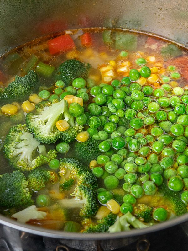 “Fresh broccoli florets, peas, and corn added to the simmering chicken vegetable soup.