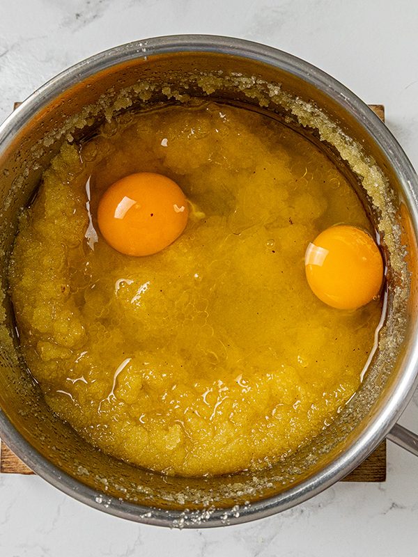 Two eggs added to a saucepan of melted butter and sugar for making brownie batter.