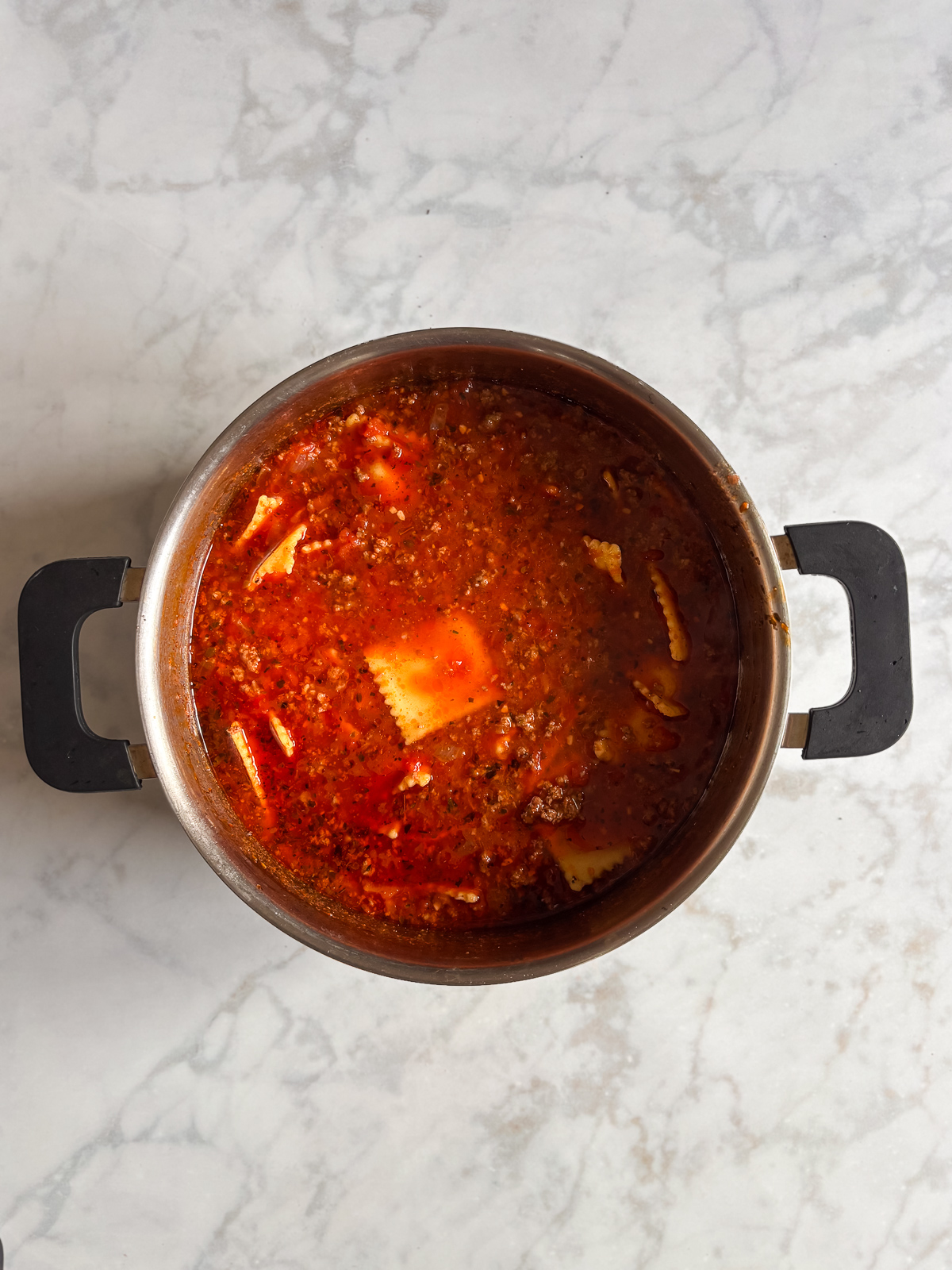 This million dollar ravioli soup is a cozy bowl of cheesy ravioli, rich tomato sauce, and tender ground beef. Simple ingredients come together in one pot, making it perfect for easy weeknight dinners. Frozen cheese ravioli added to the pot of creamy tomato soup, ready to simmer until tender.