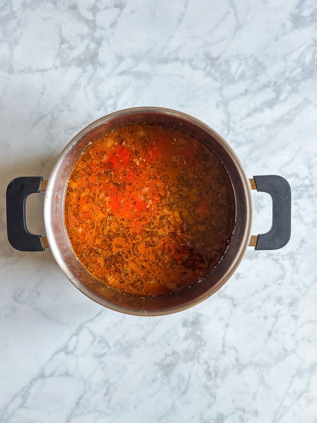 This million dollar ravioli soup is a cozy bowl of cheesy ravioli, rich tomato sauce, and tender ground beef. Simple ingredients come together in one pot, making it perfect for easy weeknight dinners. Tomato and broth mixture simmering in the pot with Italian seasonings for million dollar ravioli soup base.