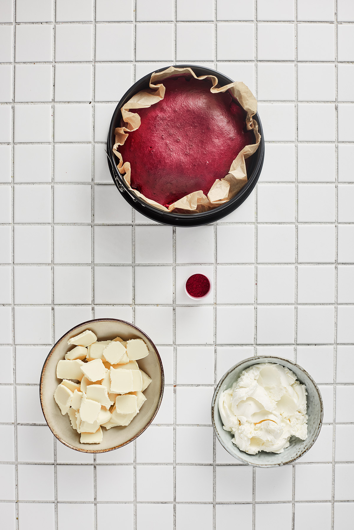 Fully baked red velvet cake cooling in a parchment-lined round pan.