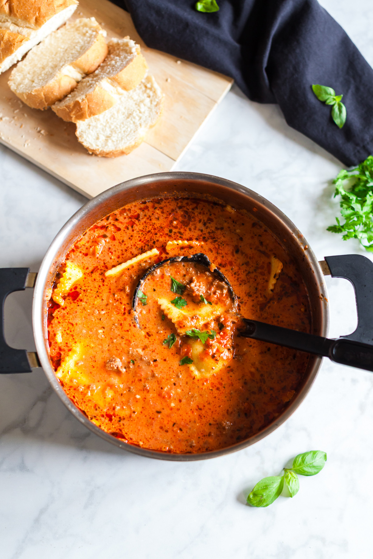 This million dollar ravioli soup is a cozy bowl of cheesy ravioli, rich tomato sauce, and tender ground beef. Simple ingredients come together in one pot, making it perfect for easy weeknight dinners. Creamy million dollar ravioli soup simmering in a pot with a ladle, showing ravioli, ground beef, tomatoes, and fresh herbs.