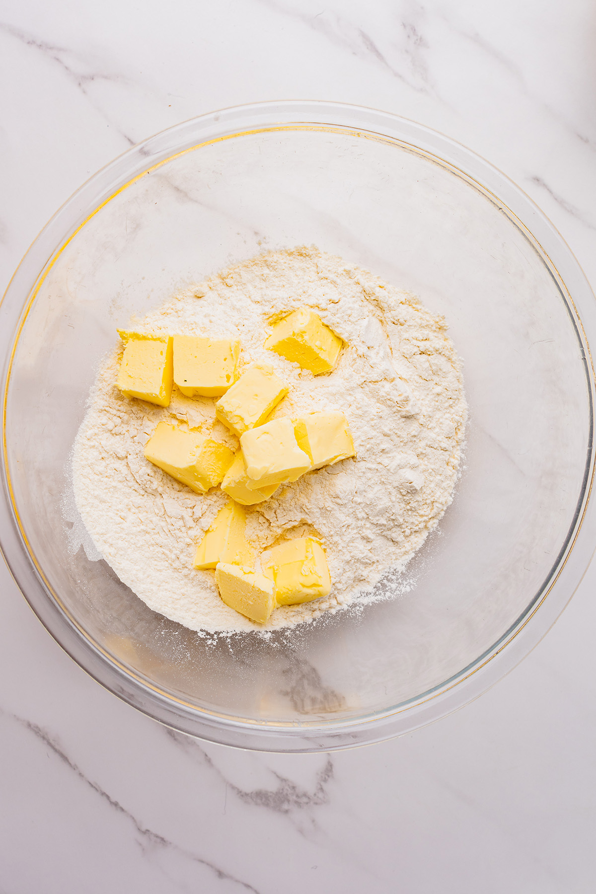 Cold cubed butter added to flour in a mixing bowl, showing the start of the arenado method for reindeer linzer cookies.