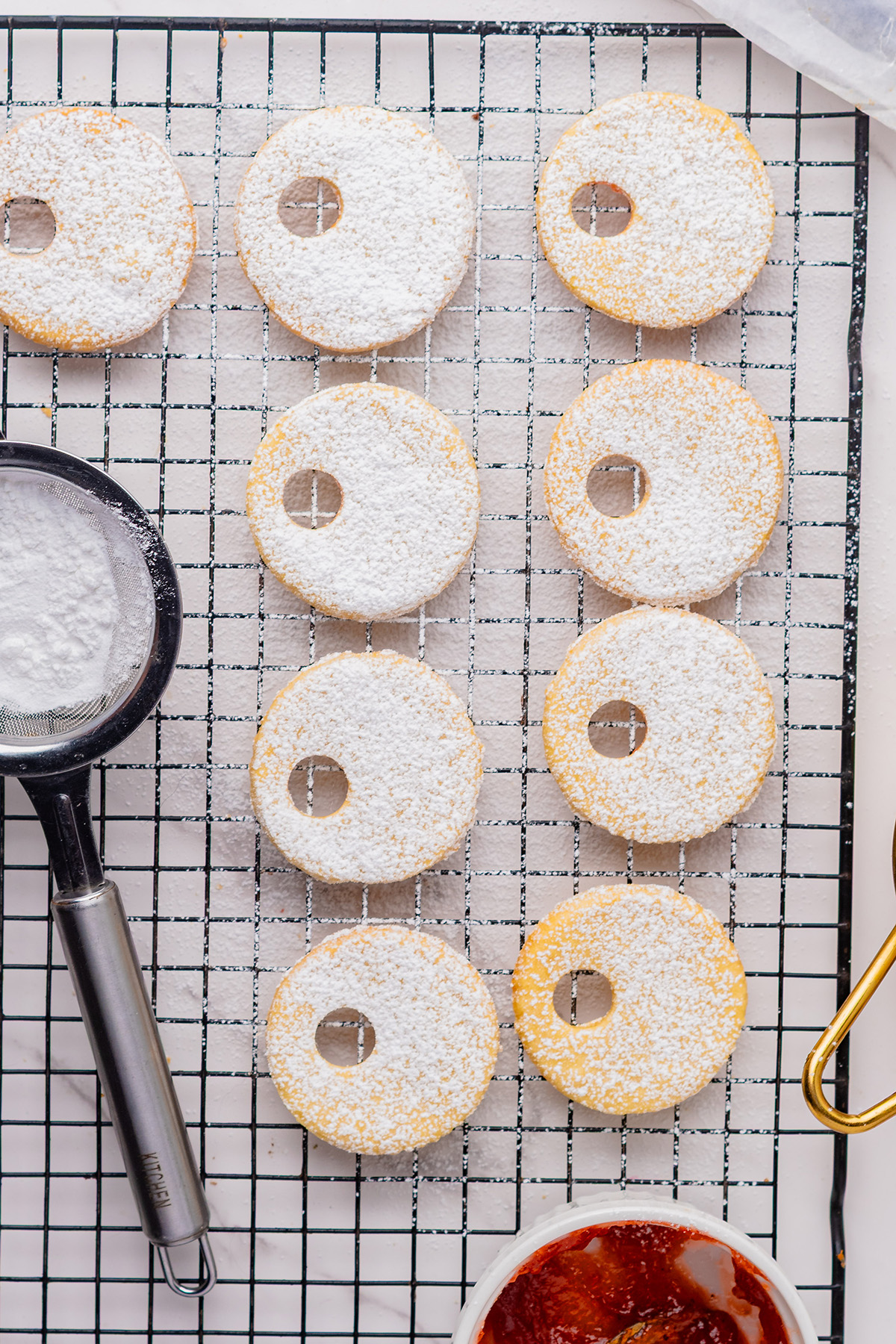 Top linzer cookie layers dusted with powdered sugar on a cooling rack, ready to assemble reindeer linzer cookies.