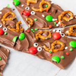 Close-up of chocolate reindeer bark broken into pieces with pretzel antlers, red noses, and holiday sprinkles.