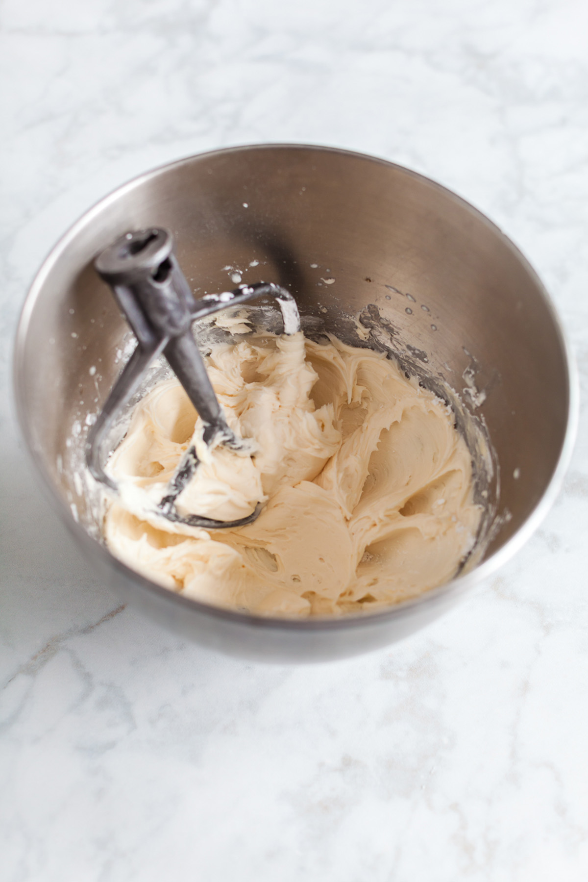 Vanilla buttercream frosting whipped in a stand mixer bowl until smooth and creamy.