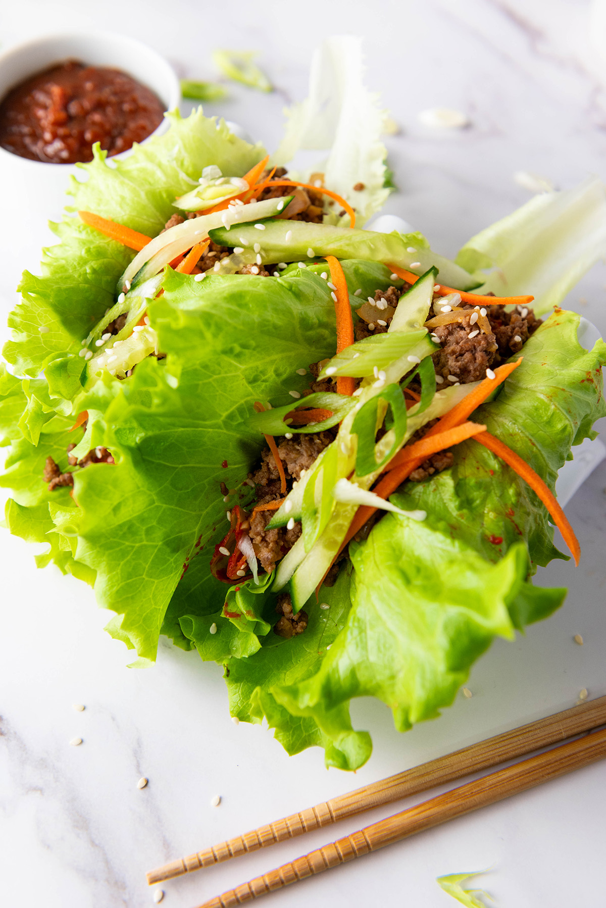 Close-up of Korean beef lettuce wraps with crisp lettuce, seasoned beef, and fresh vegetable toppings.