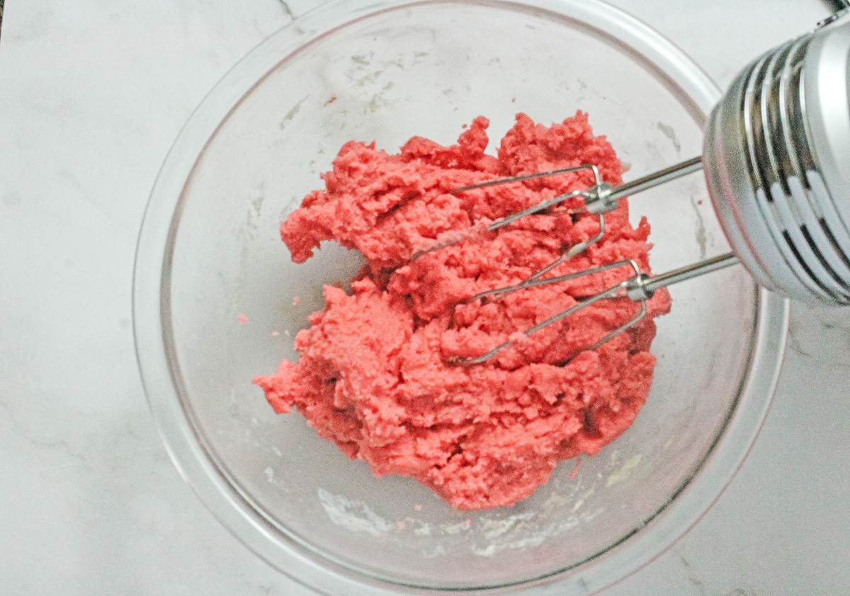 Sugar cookie dough dyed pink in a glass bowl.