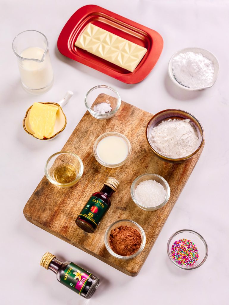 Ingredients for small batch red velvet cake pops, including flour, cocoa powder, butter, milk, vanilla, red food coloring, and sprinkles.