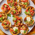 Finished taco ranch bites garnished with fresh cilantro and diced tomatoes on a serving plate.