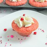Pink Valentine sugar cookie cup topped with vanilla frosting on a white plate.