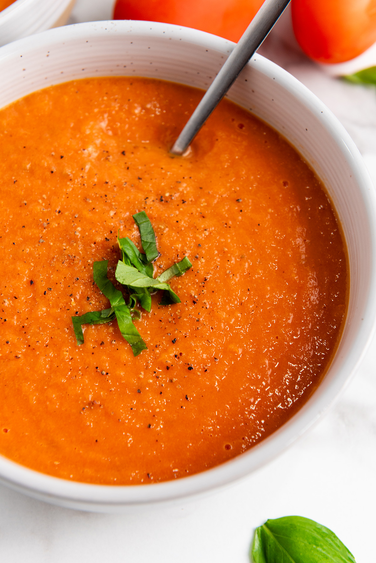 Close-up of smooth roasted tomato basil soup with basil garnish