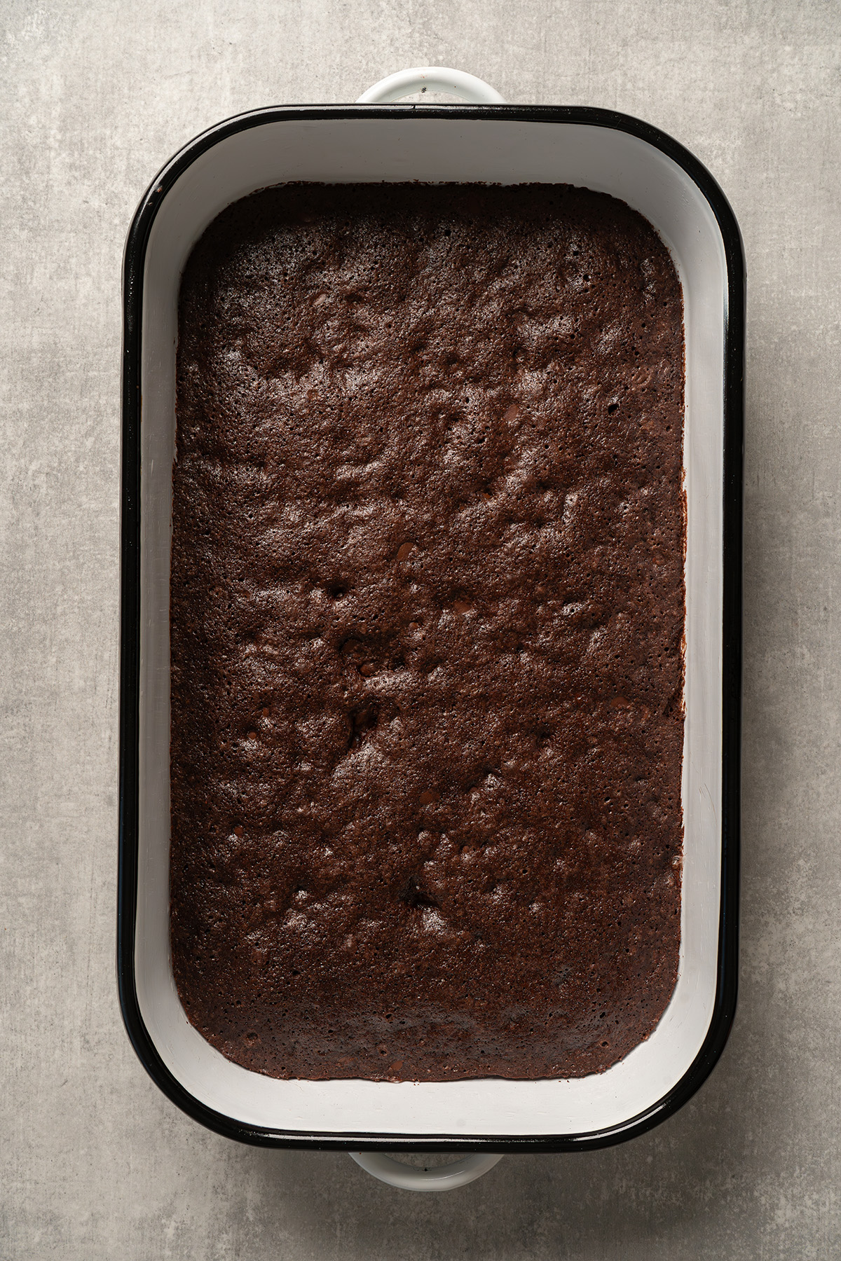Baked brownie base made from brownie mix cooling in a 9x13 baking dish.