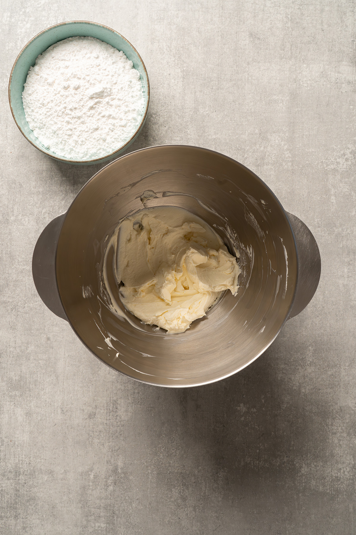 Cream cheese in a mixing bowl with powdered sugar nearby for making the French silk filling.