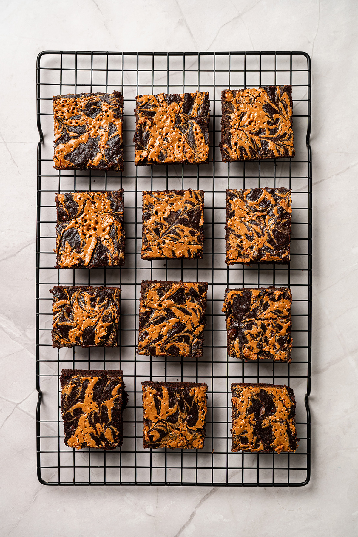 Overhead view of chocolate peanut butter swirl brownies cut into squares on a cooling rack.