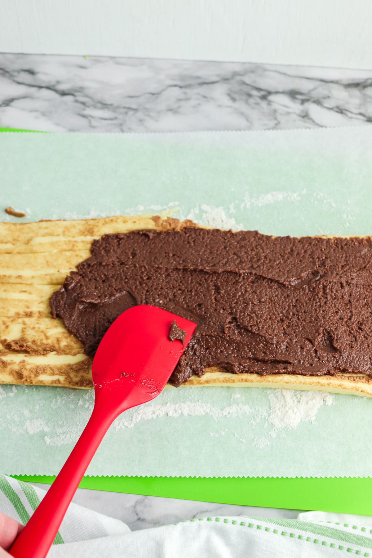 Unrolled cinnamon roll dough spread with brownie batter before rolling up for brownie cinnamon rolls.
