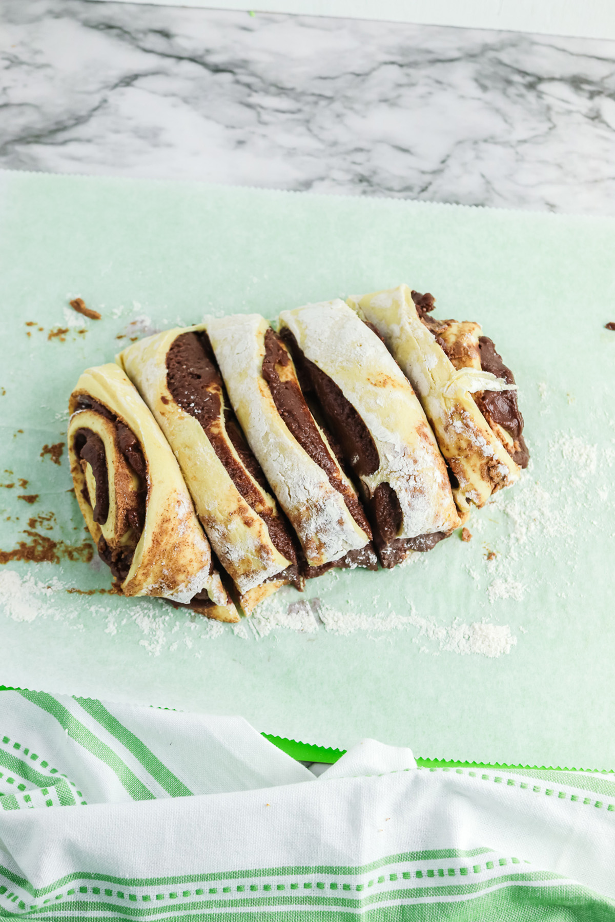 Rolled cinnamon dough filled with brownie batter sliced into sections for brownie cinnamon rolls.