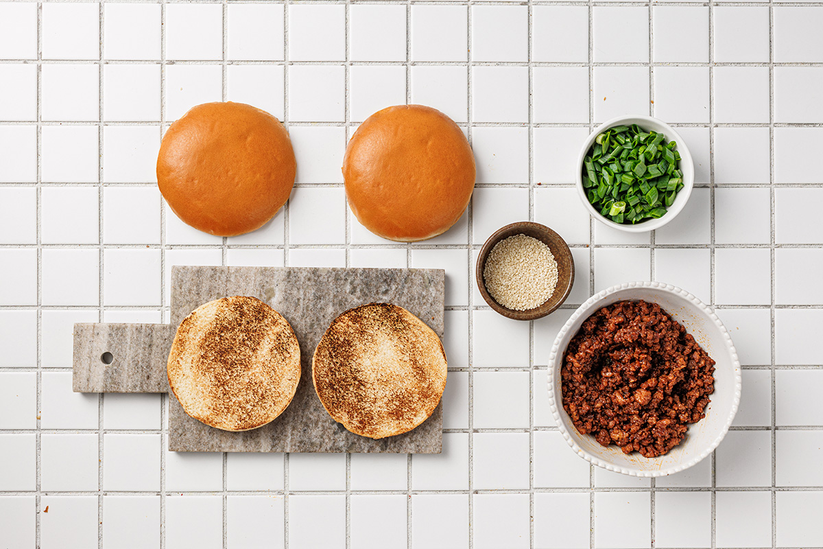 Toasted brioche buns and cooked Korean-style ground beef prepared for assembling sloppy joe sandwiches.