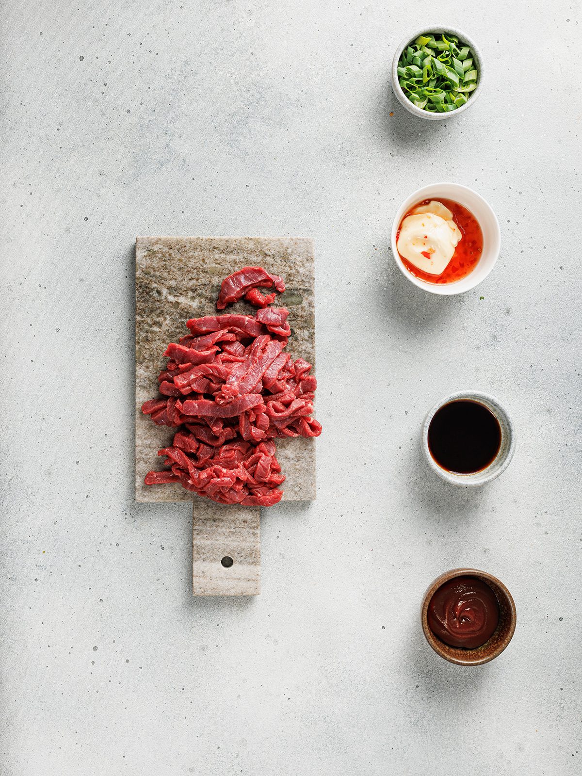 Raw sliced beef and sauces prepared for bulgogi Korean loaded fries.