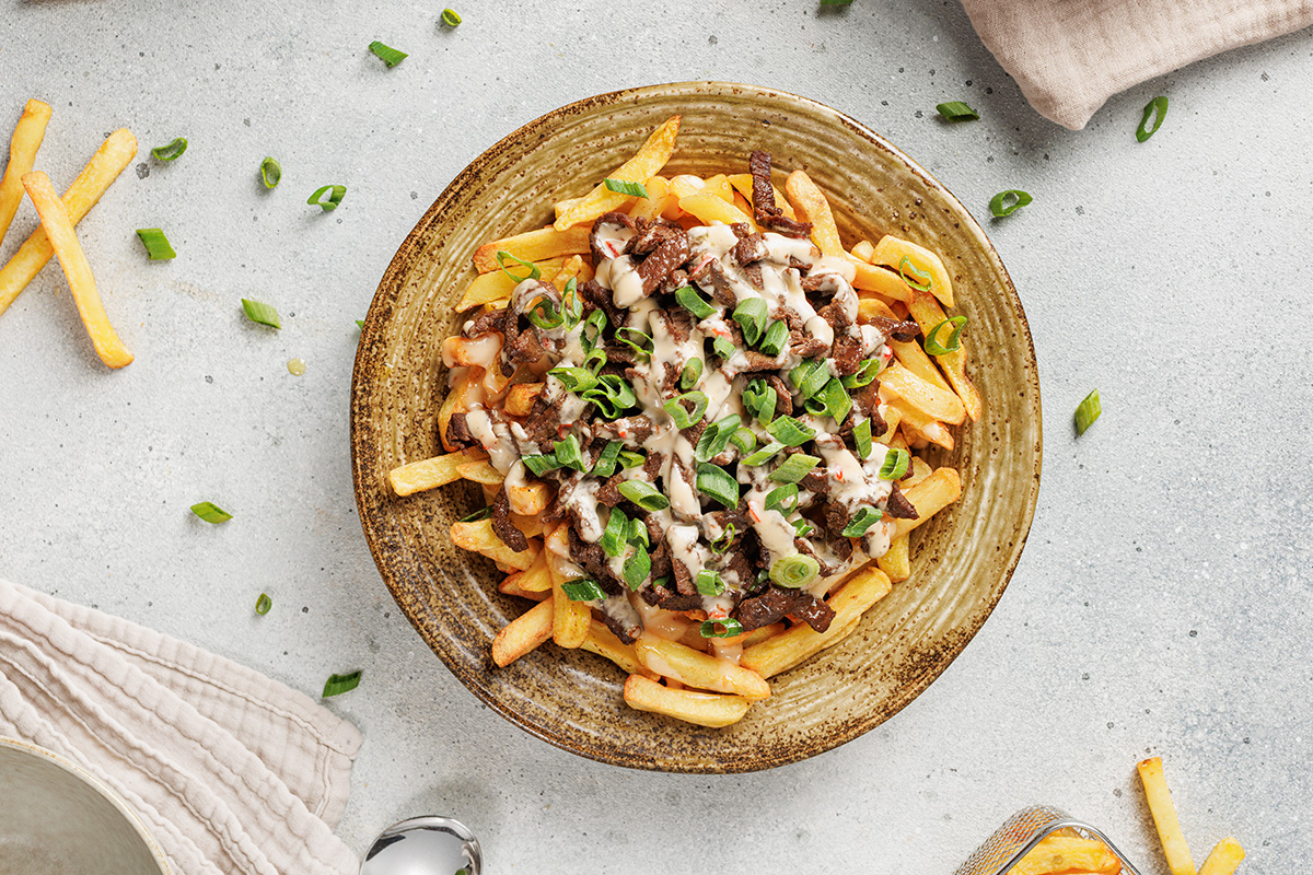 Overhead view of Korean-style loaded fries drizzled with spicy mayo.