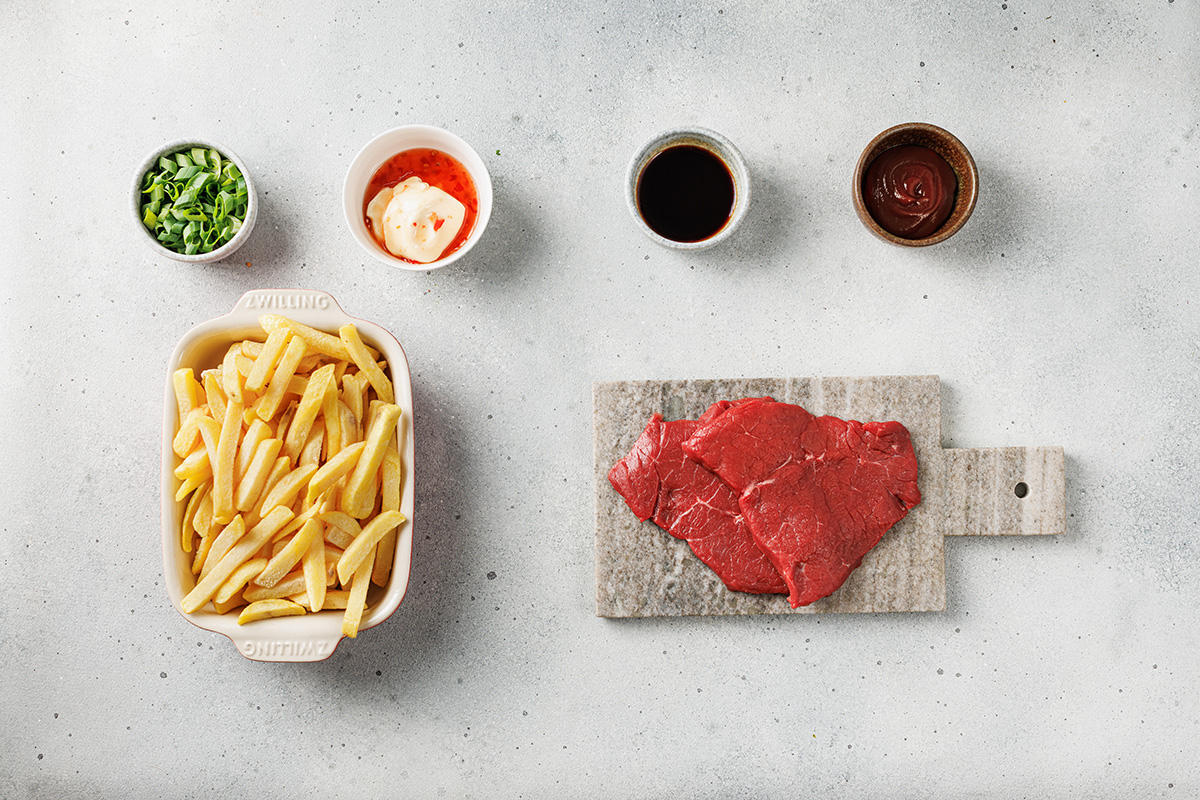 Ingredients for Korean loaded fries including sliced beef, soy sauce, barbecue sauce, sriracha mayo, green onions, and fries.
