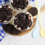 No bake oreo japanese cheesecake cups served on a wooden board with spoons.