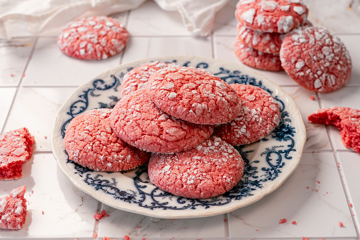 Close view of pink Easter cake mix cookies on a plate, with powdered sugar crinkle tops.