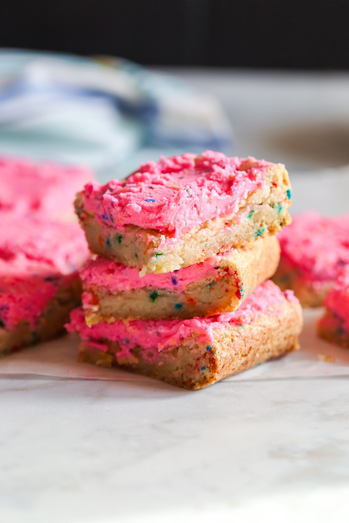 These funfetti sugar cookie bars start with a shortcut and bake up soft, buttery, and packed with sprinkles. Finished with a thick layer of pink frosting, they’re the kind of treat that disappears fast. Close up of a frosted funfetti sugar cookie bars highlighting soft crumb and creamy pink frosting.