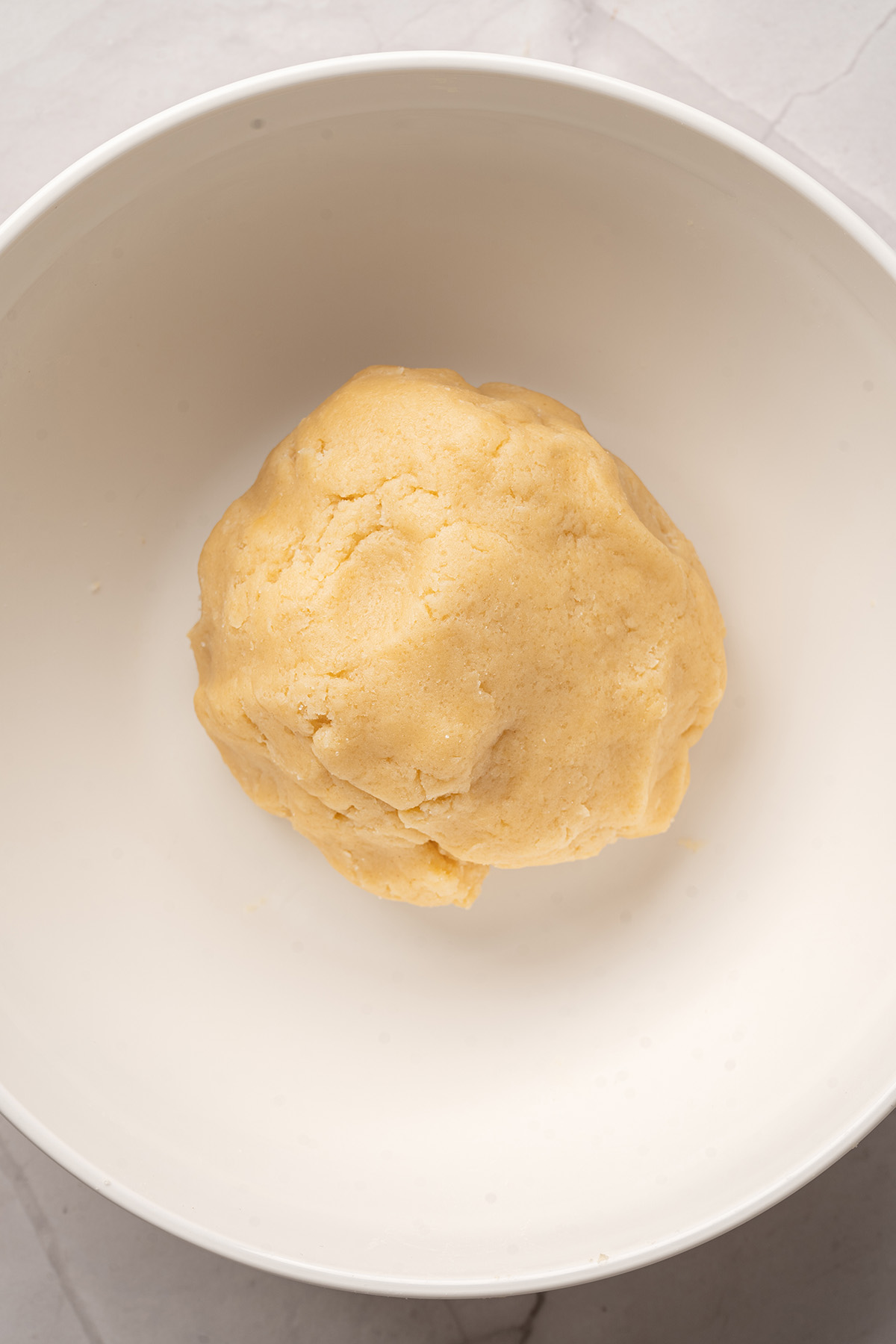 Sugar cookie blossom dough mixed in a large white bowl, ready to be rolled into balls.