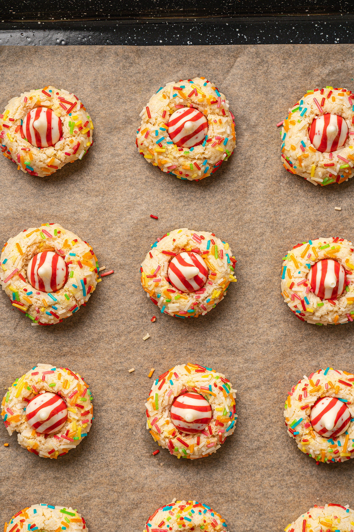 Freshly baked sugar cookie blossoms topped with Hershey’s kiss on a parchment-lined baking sheet.