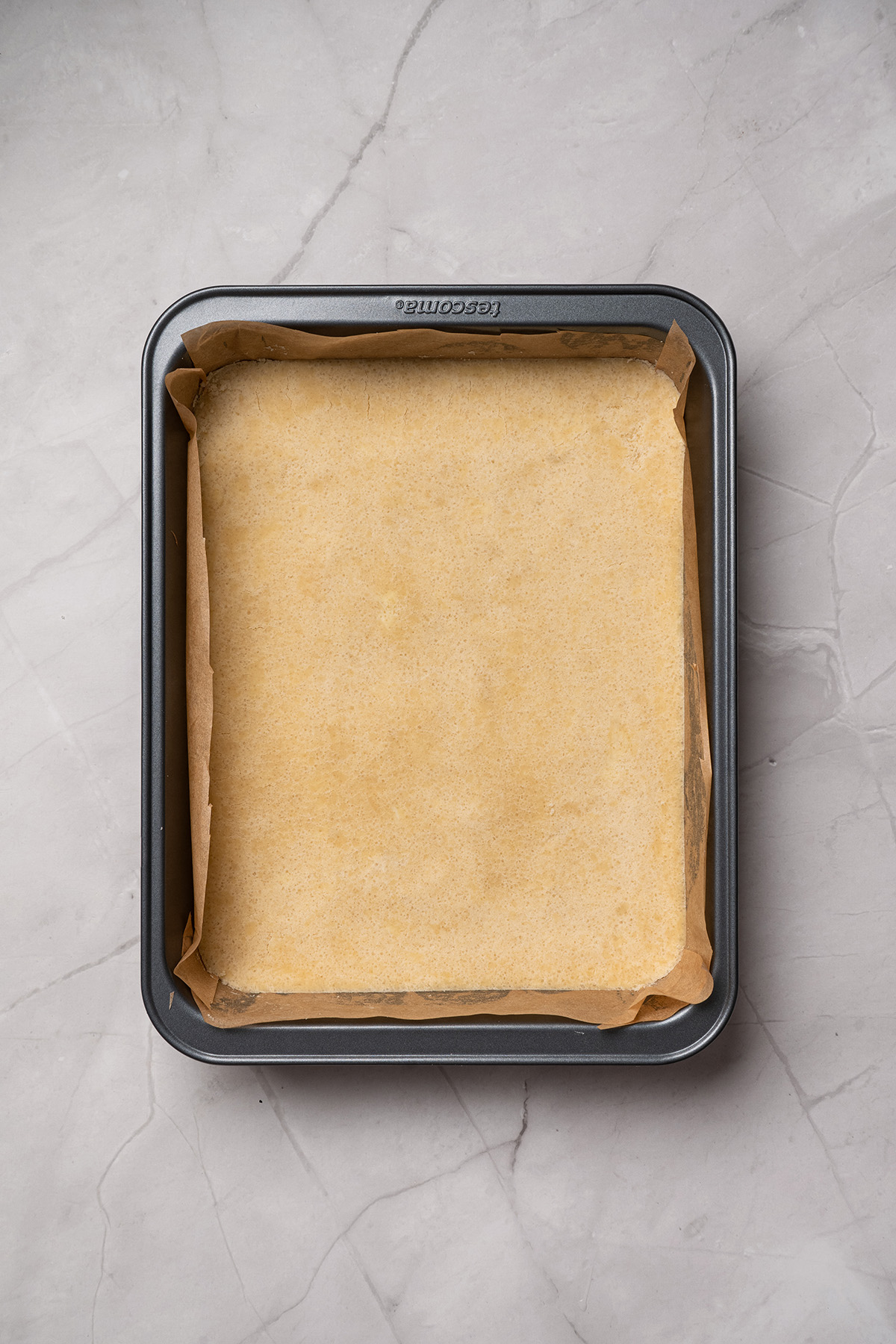 Easy sugar cookie lemon bars made with cookie mix crust, lemon juice, and zest. A sweet, tangy treat to chill and slice. Baked sugar cookie crust in a parchment-lined pan.