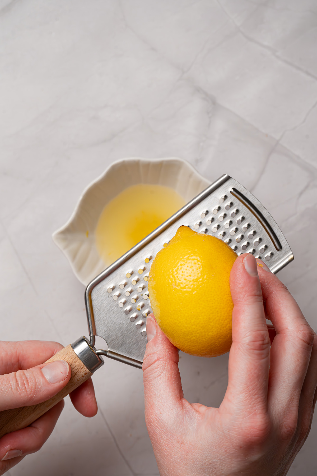 Easy sugar cookie lemon bars made with cookie mix crust, lemon juice, and zest. A sweet, tangy treat to chill and slice. Zesting a fresh lemon with a handheld grater for lemon bar filling.