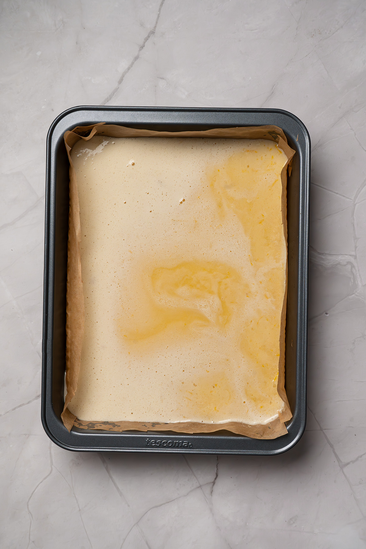 Easy sugar cookie lemon bars made with cookie mix crust, lemon juice, and zest. A sweet, tangy treat to chill and slice. Unbaked lemon bars in the pan after adding the lemon filling.