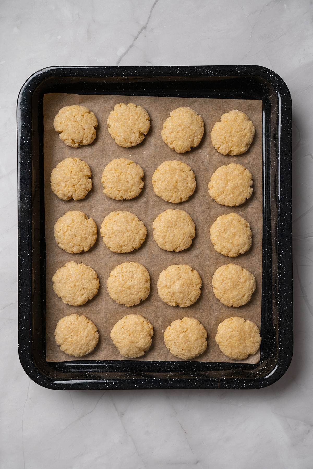 These cream cheese sugar cookies are soft, sweet, and topped with fluffy frosting. Starting with sugar cookie mix keeps them easy, but they still feel special enough for parties and holidays. Baked cream cheese sugar cookies on a parchment-lined baking sheet, lightly golden and slightly crackled.