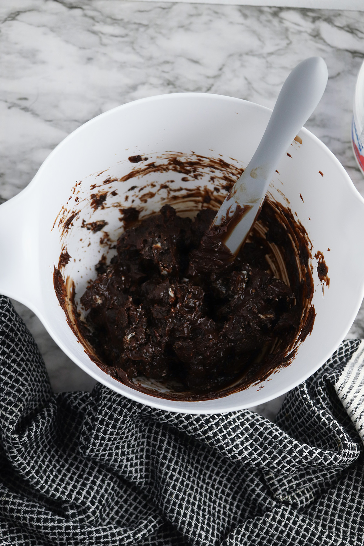 Hot fudge and crushed Oreo cookies mixed together in a white bowl for Klondike ice cream cake.